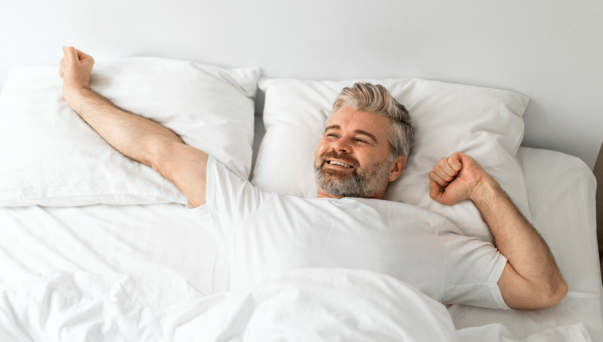 happy mature man lying in bed stretching after wa 2023 11 27 05 05 15 utc